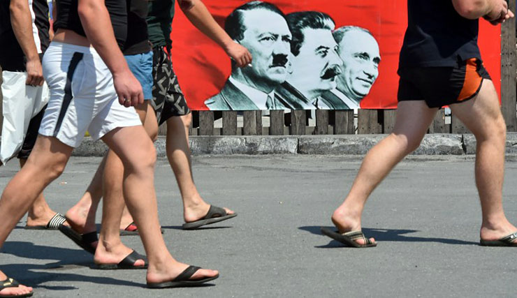 Járókelők haladnak el egy Hitlert, Sztálint és Putyint közösen ábrázoló plakát előtt a kijevi Függetlenség téren